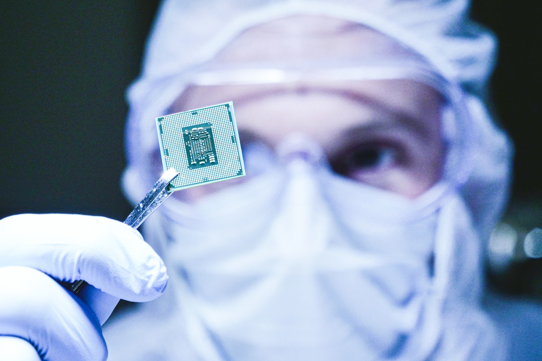 Ingenieur schaut sich einen Chip in Reinraumkleidung an.
