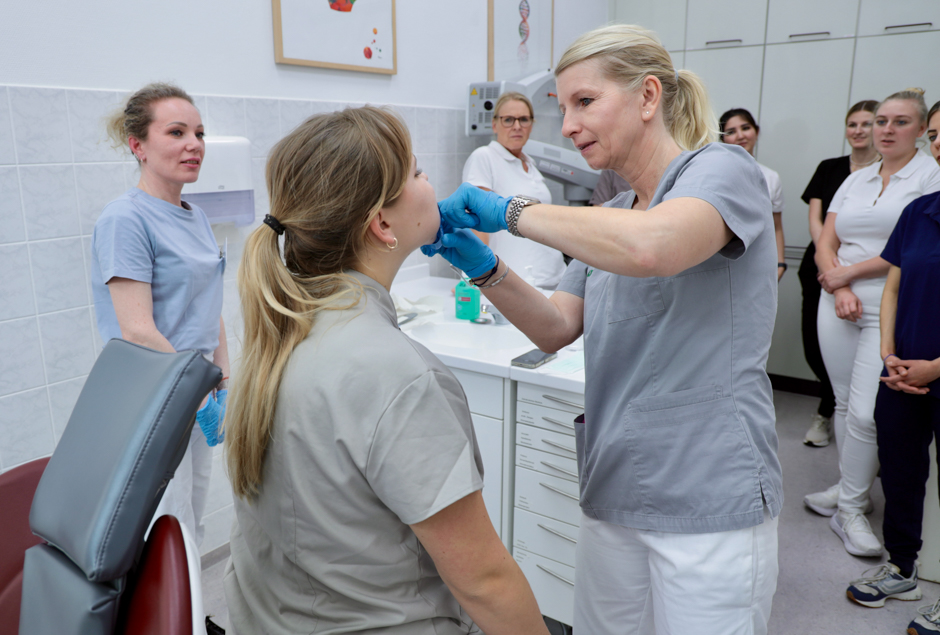 Eine Zahnärztin zeigt einer Gruppe von Auszubildenden eine Untersuchung im Mund einer Patientin.