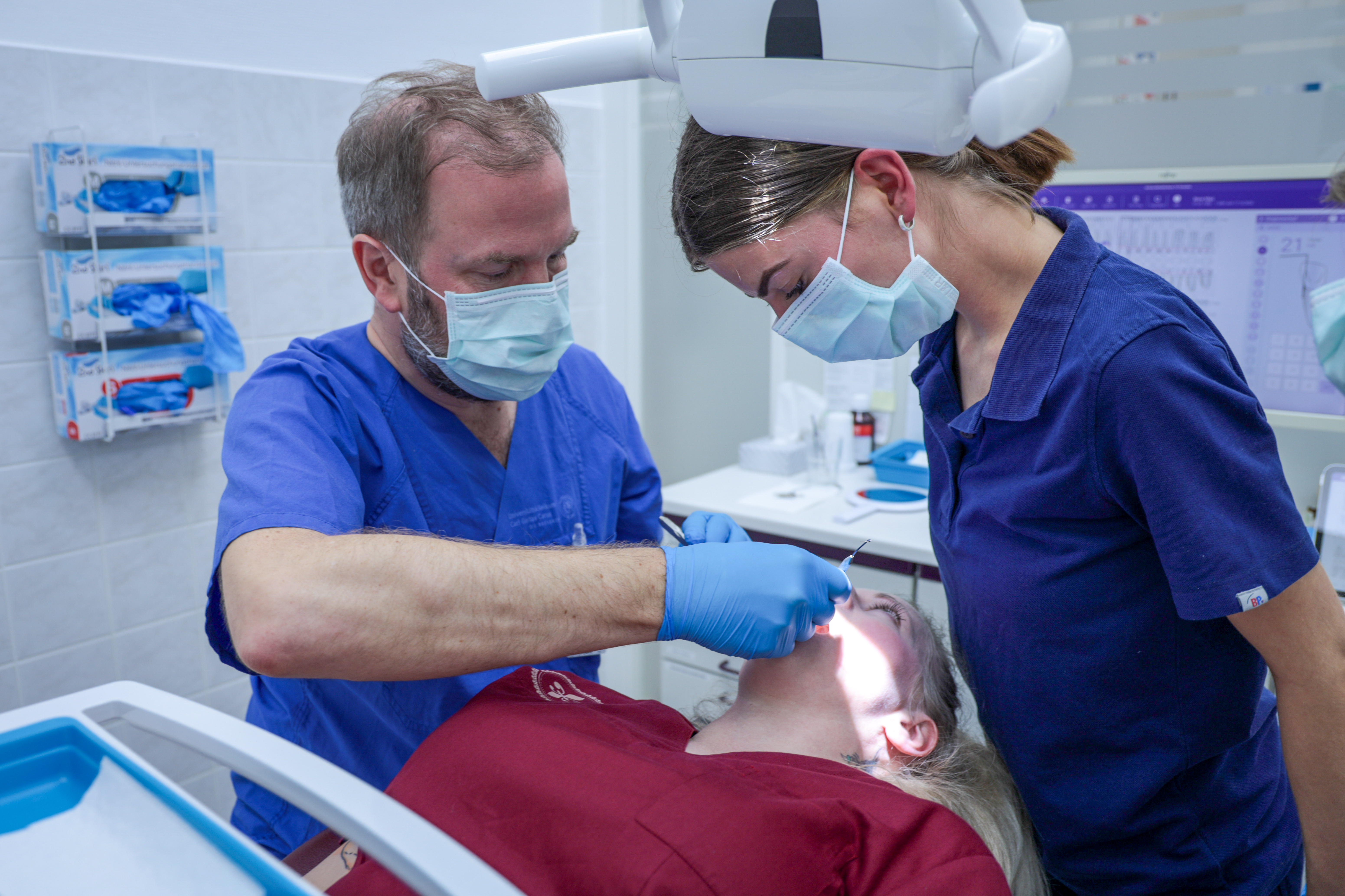 Zwei Ärzt:innen behandeln Patient in Zahnarztklinik.