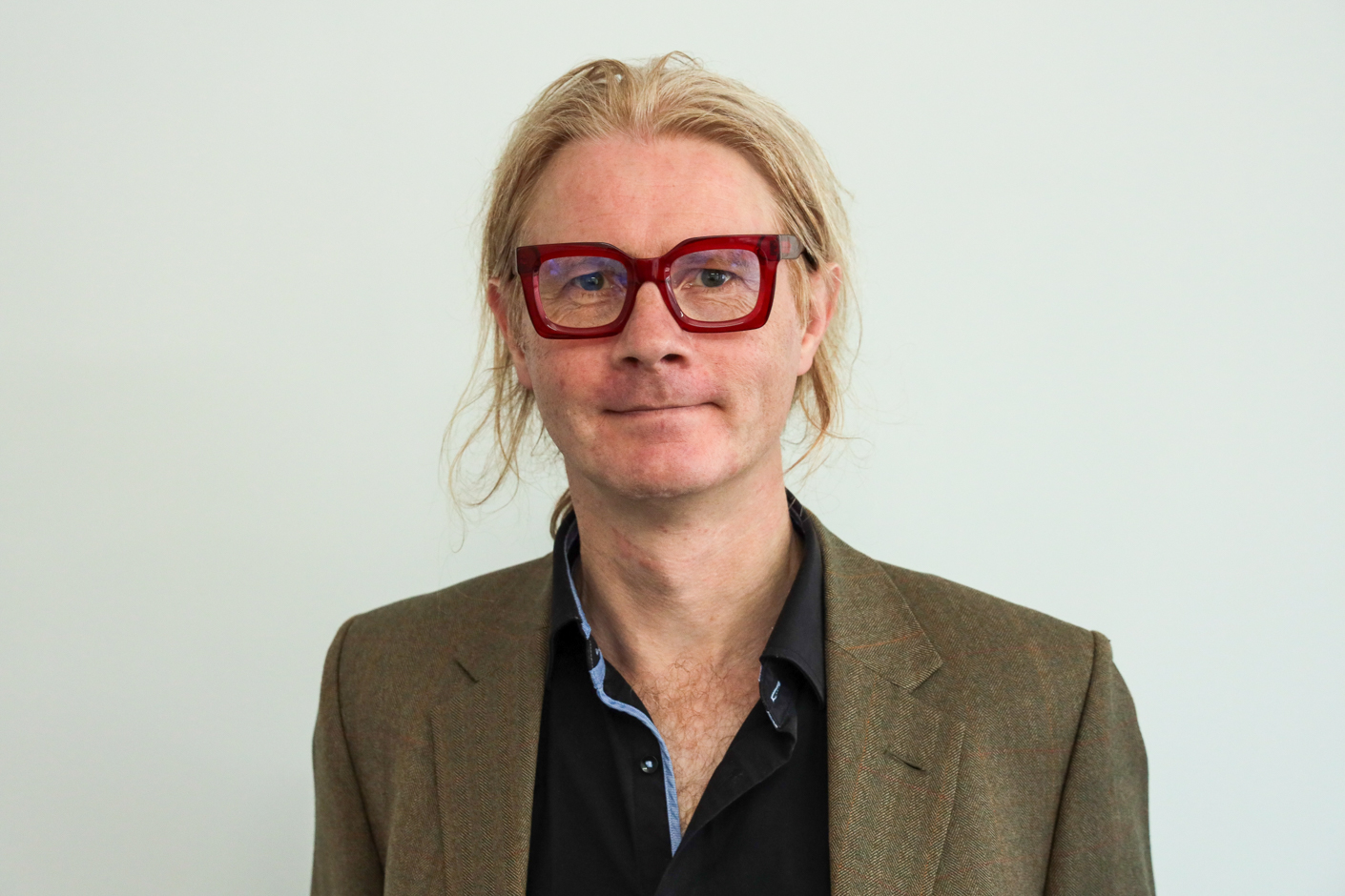 Mann mit Jackett und großer Brille.